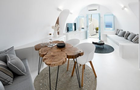 Τhe interior of the superior villa of Dana Villas with the white color and the dining table made of tree trunks to dominate