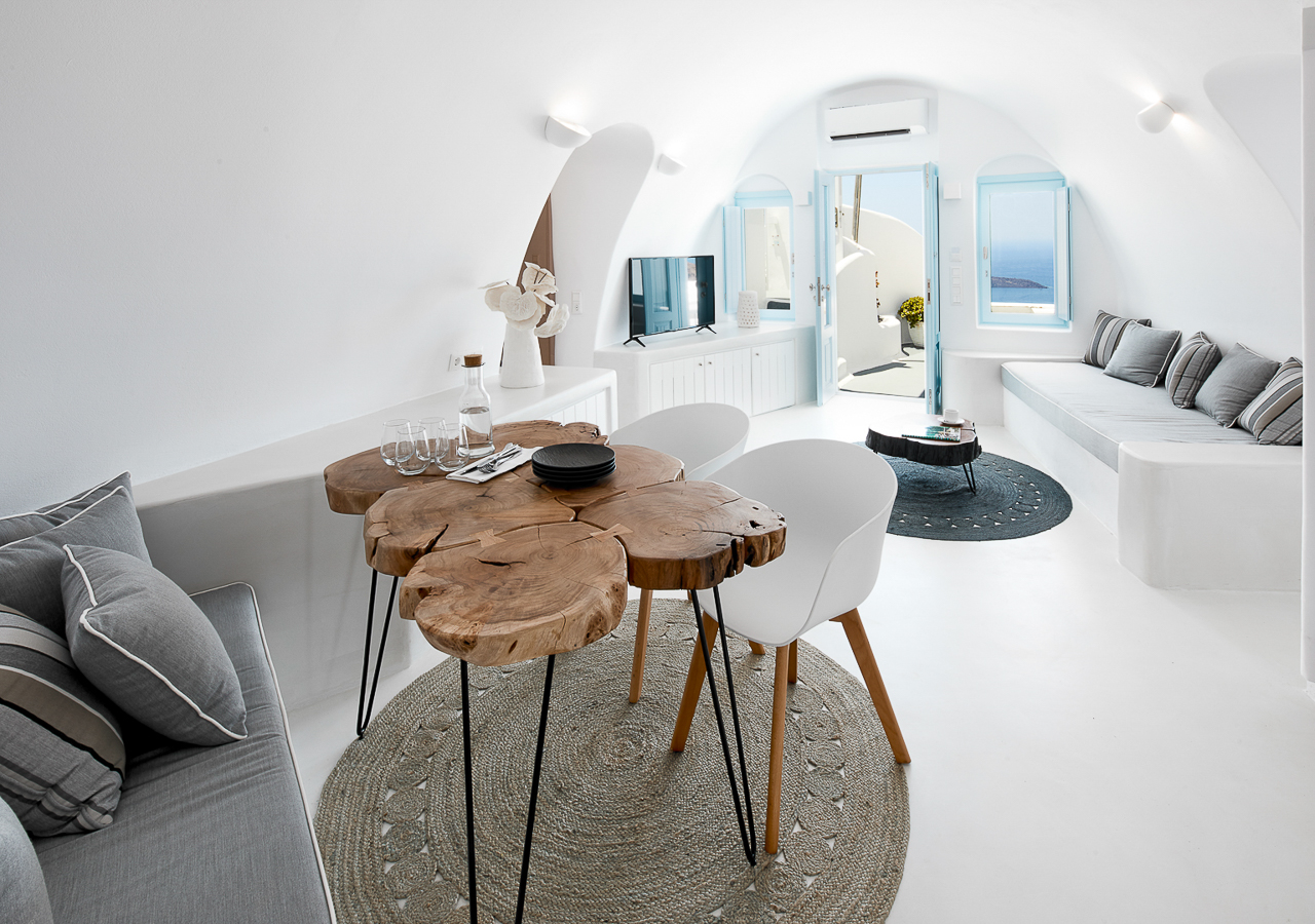 Τhe interior of the superior villa of Dana Villas with the white color and the dining table made of tree trunks to dominate