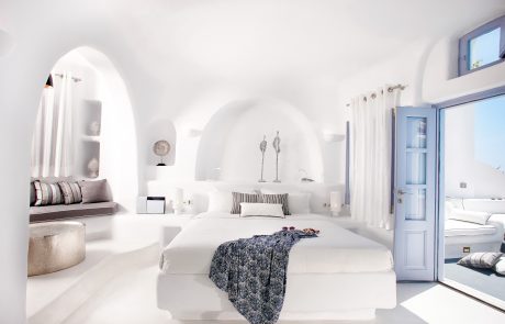 bright suite with white walls and floor, blue windows, built-in bed and sofa and a gold coffee table