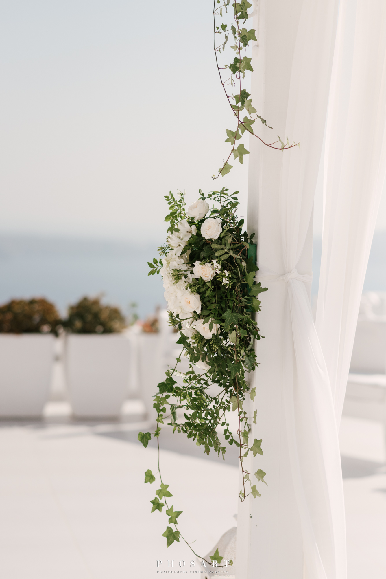 A bouquet of white flowers and ivy on a white curtain made of  gauze