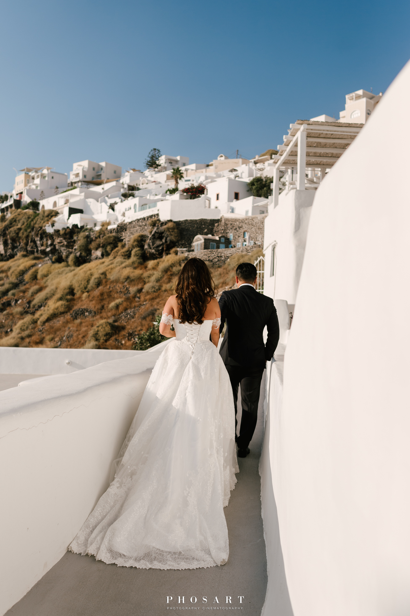 Α newlywed couple walking in the alleys of the caldera, Santorini, in a black and white photo