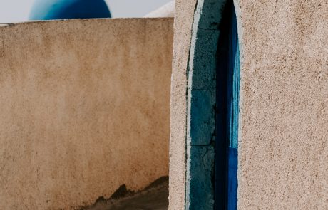 An artistic snapshot from an alley in Santorini with a dome in the background