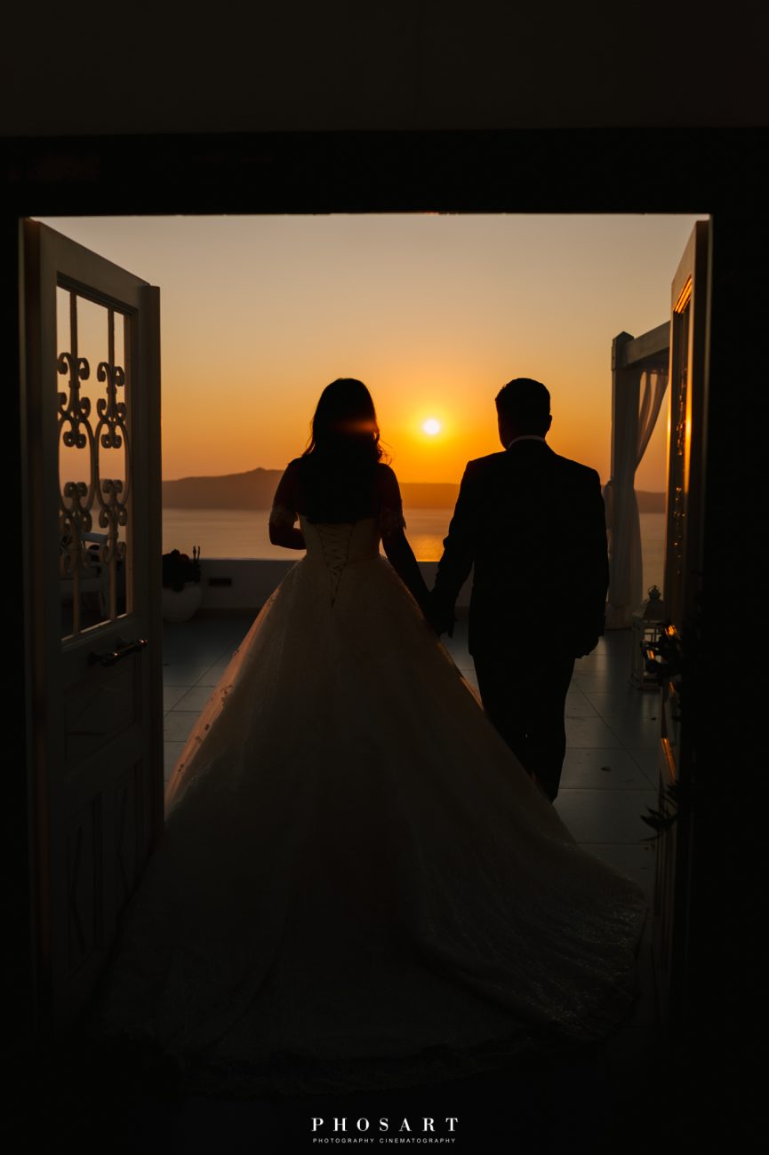 Newlyweds enter Dana Villas Santorini main gate as the sun sets