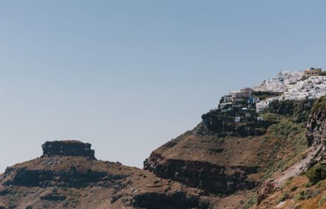 The steep cliffs with the red black color and the white houses in Santorini
