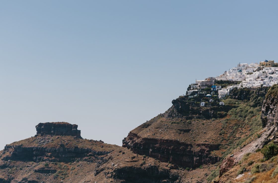 The steep cliffs with the red black color and the white houses in Santorini