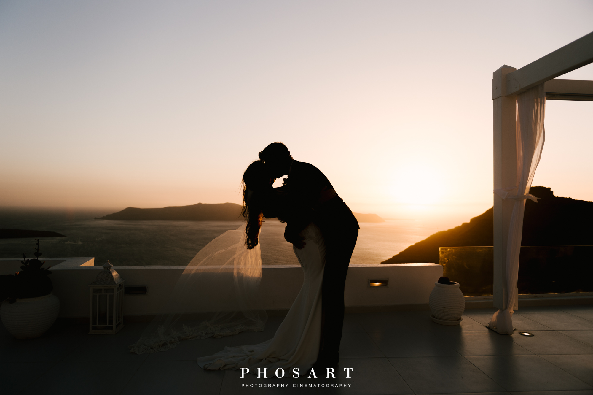 Newlywed couple kissing on the terrace of Dana Villas during sunset
