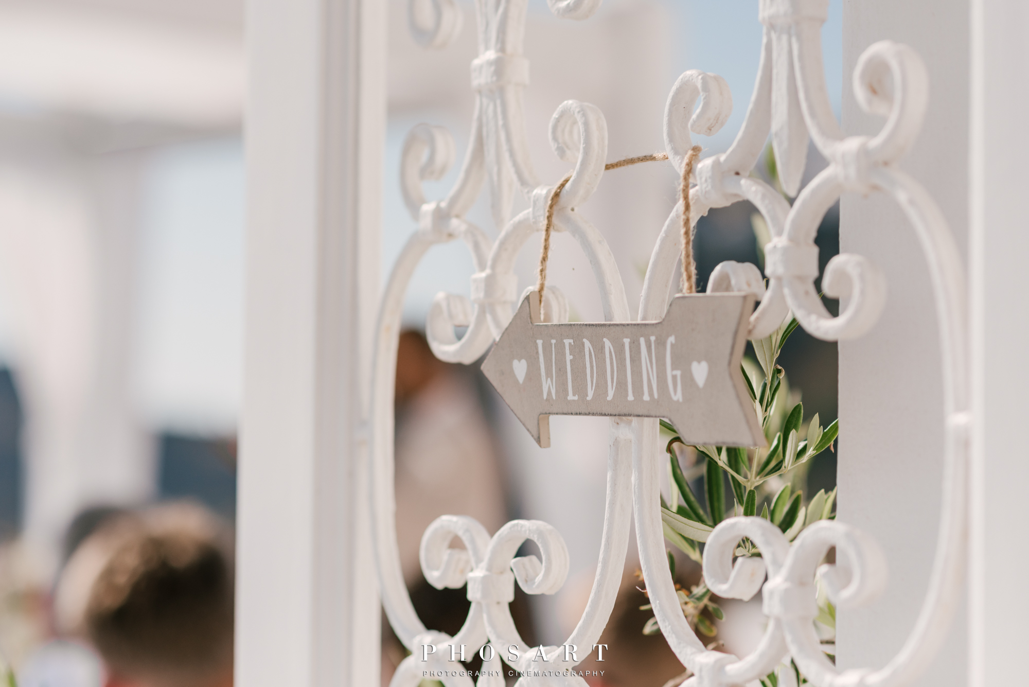 Close-up from the white iron entrance door of Dana Villas with a small wooden arrow shaped sign that writes wedding