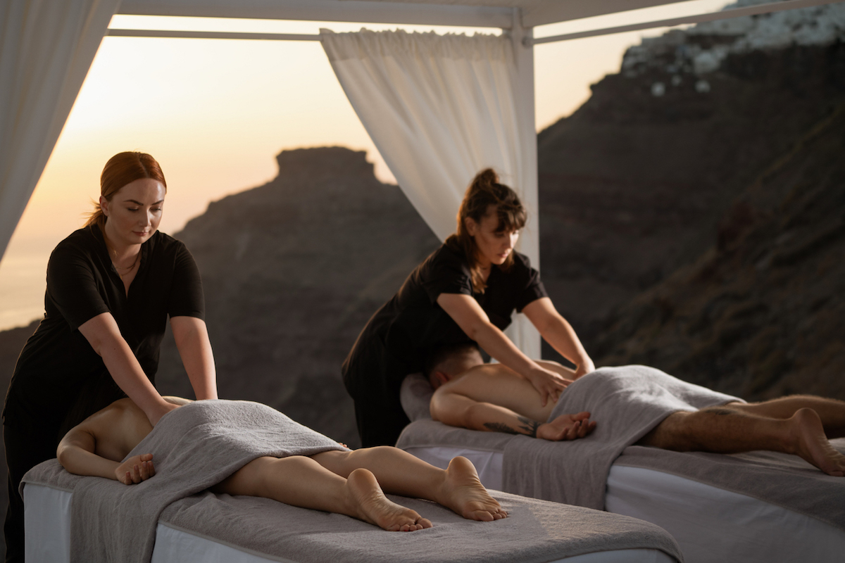 Α couple enjoys a relaxing massage on the terrace of Soma Spa overlooking Caldera during sunset