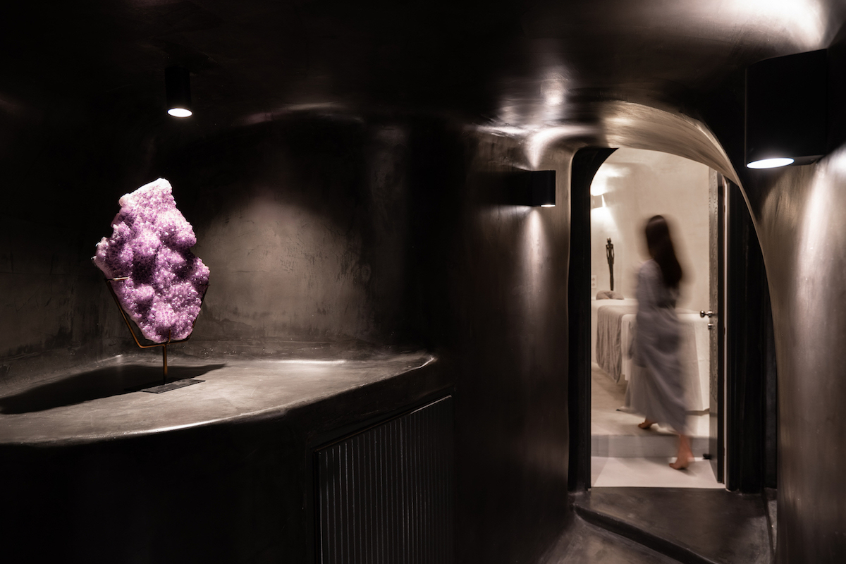 Dark image from Soma Spa space with black walls & floors and a decoration sculpture made of amethyst under a beam of light